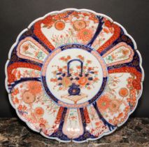A Japanese scalloped circular charger, painted in the Imari palette with central floral vase
