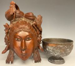 An Indonesian carved hardwood wall mask, female in traditional headdress with bird companion,