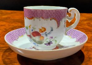A Meissen coffee cup and saucer, painted with ripening fruit and nuts, under a puce scale border,