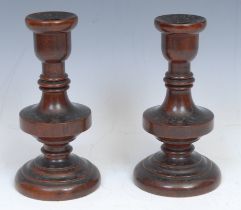 Treen - a pair turned fruitwood candlesticks, 18cm high