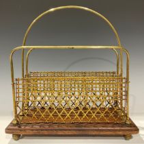 A Victorian brass magazine rack, three brass wire work panels, oak base, brass bun feet, 38cm