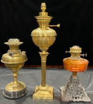 A Corinthian column brass oil lamp; a brass oil lamp; an amber glass oil lamp