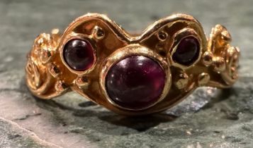 An 18ct gold garnet ring, set with three circular cabochon red garnets, shaped scrolling crest, 18ct