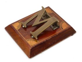 An Edwardian mahogany and brass novelty letter clip, as a letter M, the spreading rectangular base
