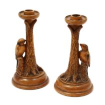 A pair of early 20th century sculptural walnut candlesticks, each carved with a woodpecker at a tree