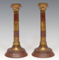 A pair of Egyptian Revival red marble and lacquered brass columnar candlesticks, 18cm high, c. 1870