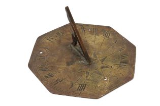 A 19th century brass octagonal sundial, engraved with sun-in-splendour and Roman numerals, and