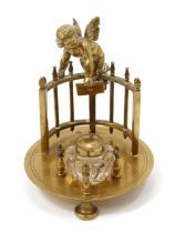 A 19th century brass novelty inkstand, cast with Cupid delivering a love letter, fluted clear