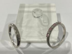 A platinum engagement ring, set with three brilliant cut diamonds, interspersed with pink stones,