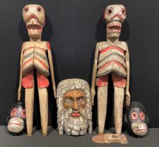 A pair of Mexican 'Day of the Dead' carved hardwood skeletons, articulated arms, painted in tones of