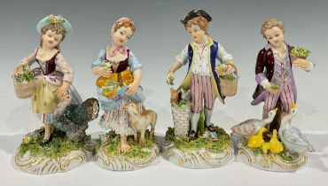 A set of four Naples porcelain figures, as boy and girl farmhands hand feeding livestock, painted in