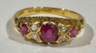 An 18ct gold ring set with three graduated faceted rubies, interspersed with four diamond chips,