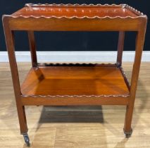 An early 20th century mahogany two-tier buffet serving trolley, each rectangular plateau with wavy