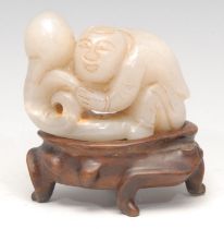 A Chinese jade carving, of a figure holding a peach, 6.5cm wide, hardwood stand