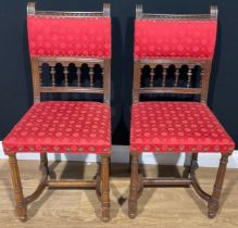 A pair of Arts and Crafts oak side chairs, the spindle centred ladder backs applied with fabric,