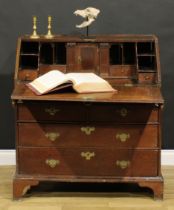 An early George II oak bureau, fall front enclosing a well, a small door, small drawers, pigeonholes