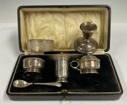 A silver three piece cruet set; a silver candlestick; a silver bangle