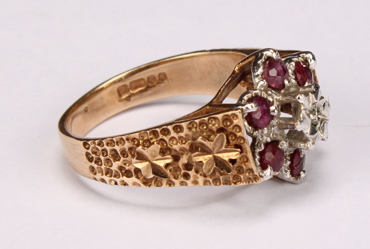 A ruby and diamond flowerhead ring, the central round facet cut stone claw set above six round facet - Image 2 of 5