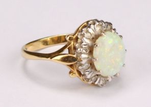 An 18ct gold opal and diamond cluster ring, the central polished oval opal cabochon surrounded by