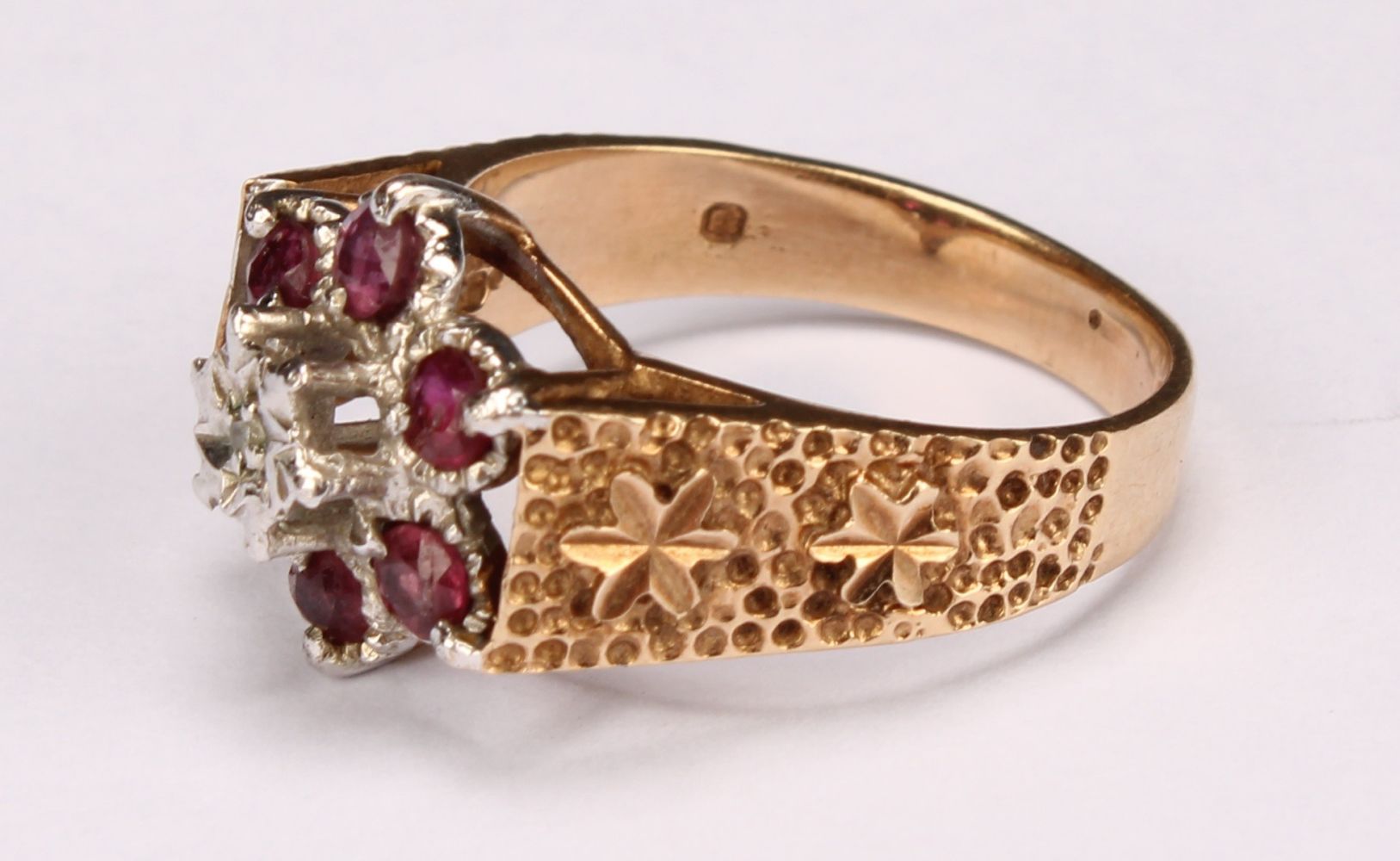 A ruby and diamond flowerhead ring, the central round facet cut stone claw set above six round facet - Image 3 of 5