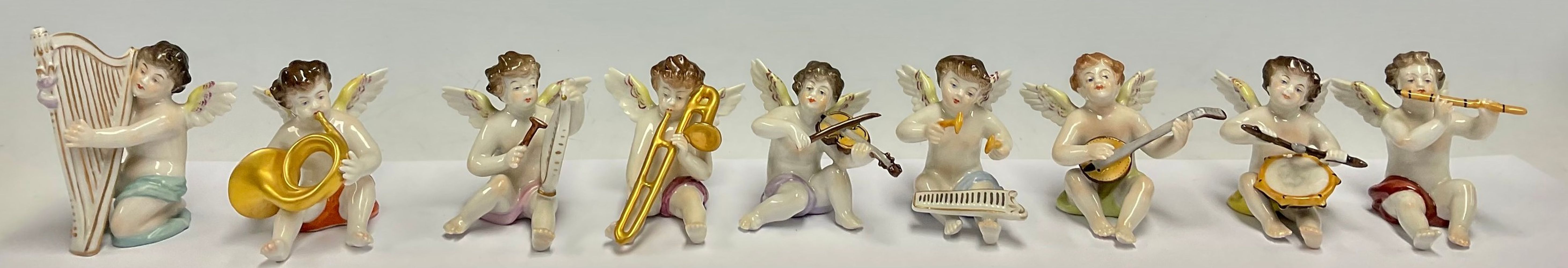 A Dresden porcelain miniature angelic band group, each cherub with a musical instrument, comprising,