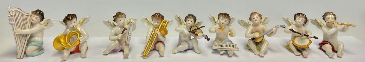 A Dresden porcelain miniature angelic band group, each cherub with a musical instrument, comprising,