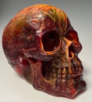 An amber coloured resin Skull, all over decorated with Celtic scrolls and motifs, approx. 13.5cm