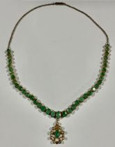 A gold plated necklace, set with a strand of graduated faceted oval emeralds, suspended with a