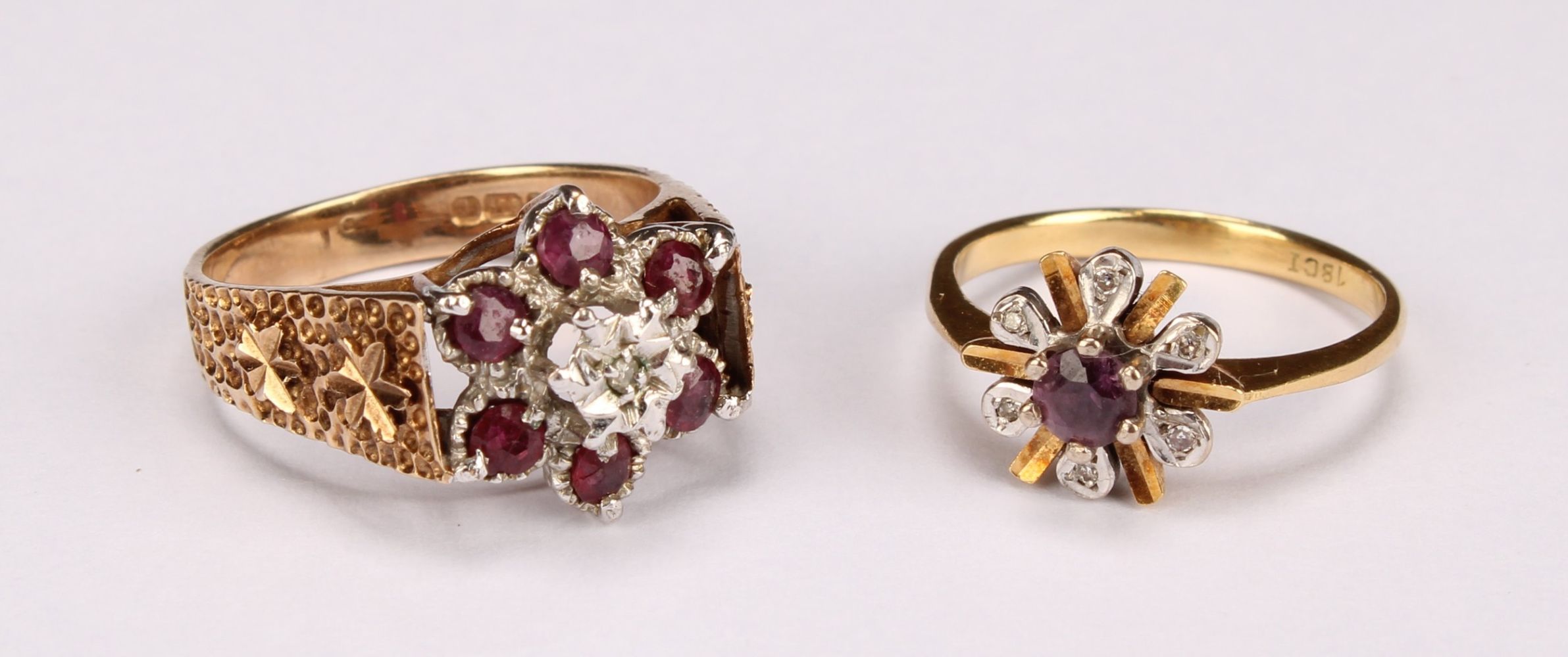 A ruby and diamond flowerhead ring, the central round facet cut stone claw set above six round facet