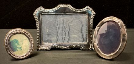 An Edwardian style shaped top silver photograph frame, London 1988, two others smaller oval (3)