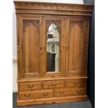 A Gothic style pine triple wardrobe, central dressing mirror door, flanked by a pair of doors with