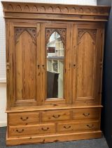 A Gothic style pine triple wardrobe, central dressing mirror door, flanked by a pair of doors with