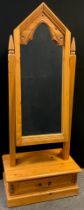 A Gothic style pine Cheval mirror, the mirror having a carved Gothic arch top, single drawer to
