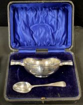 A George V silver twin handled Quaich and spoon, Chester 1911, 5.210zt, cased.