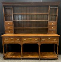 A George III style oak dresser, the boarded back with shelves and six short drawers, below a