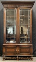 An early 20th century oak bookcase cabinet, outswept cornice, pair of glazed leaded doors