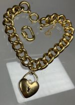 A heavy solid link yellow metal twist link bracelet, 23cm long, 1cm wide, suspending a heart