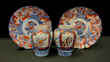 A pair of Japanese Imari plates, traditionally decorated with gardens flowers and trellis panels,
