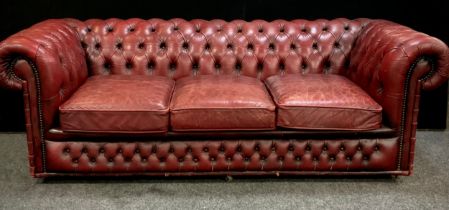 An Oxblood red leather chesterfield three seater sofa, 67cm high, 200cm wide, 90cm deep, seat height