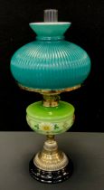 A Victorian brass and painted green opaque glass oil lamp, floral painted reservoir, stepped brass
