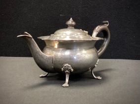 A George V silver teapot, pie crust rim, ovoid body, paw feet, ebony handle, marks worn probably