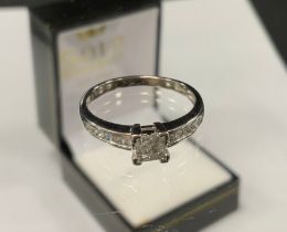 A diamond cluster ring, with four stone princess cut diamond centre above round brilliant cut