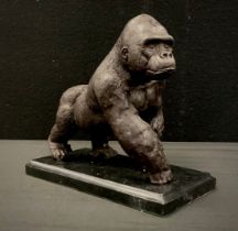 A bronzed metal model of a gorilla on black marble plinth, 20cm long