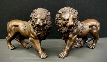 A pair of standing bronzed metal lions, 33cm long (2)