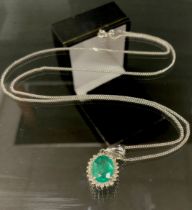 An emerald and diamond cluster pendant necklace, central oval emerald approx 0.88ct, surrounded by a