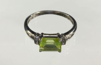 A peridot and diamond ring, central emerald cut peridot between round brilliant cut diamonds, 9ct