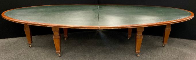 A very large mahogany boardroom table, the oval shaped top with green leatherette inset surface,