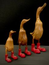 A set of three graduated novelty wooden geese with red boots, 28cm to 46cm high (3)
