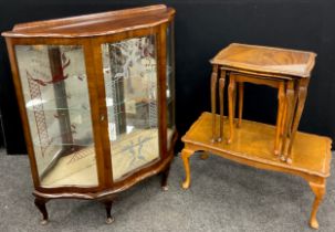 A 1950’s walnut display cabinet, shaped bow-front, glazed door enclosing two tiers of glass