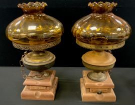 A pair of oil lamp table lamps, later converted to electricity/candles, amber glass shades, brass